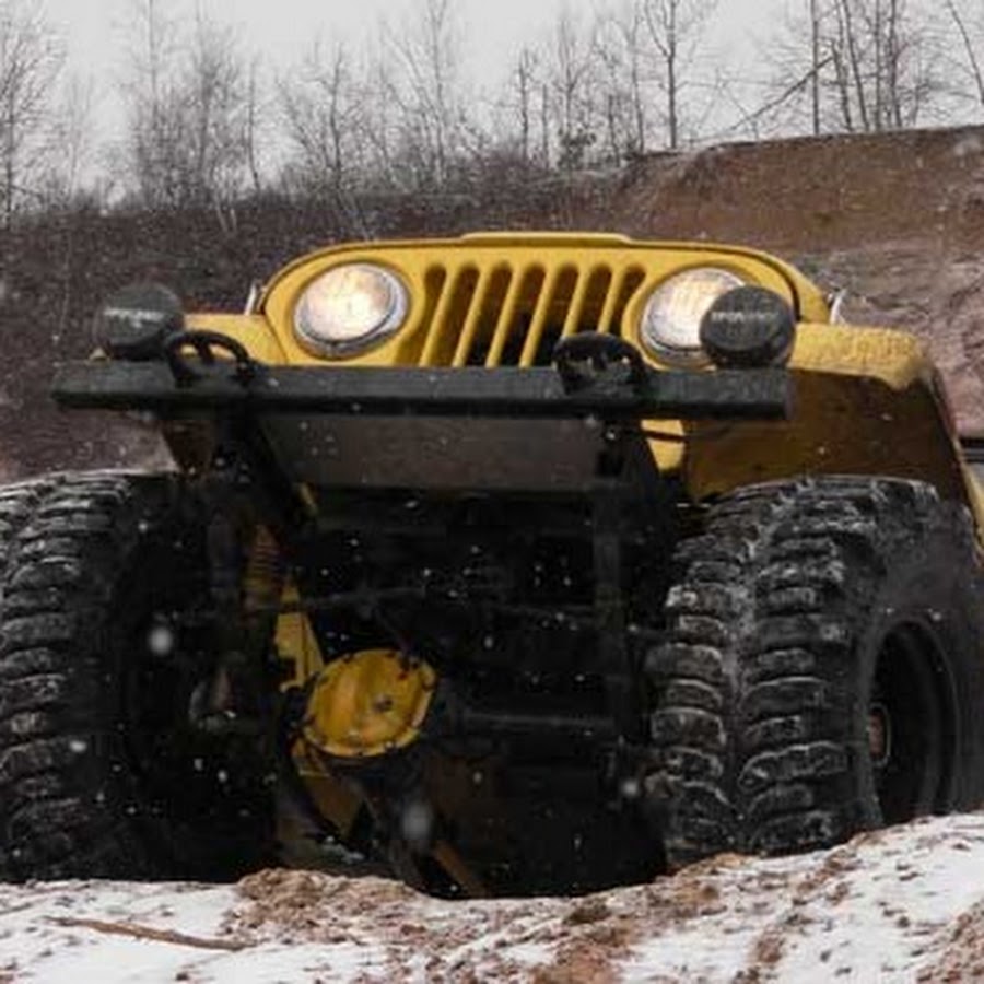 Yellow Jeep flexing its suspension on rough snowy ground